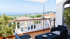 A balcony with a white railing, wicker furniture, and a view of the sea and distant buildings. - Villa Maria, incredible sea views, relax, swimming pool, wifi, barbecue, garden (alaior)