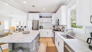Una cocina moderna con armarios blancos, encimera de mármol y horno empotrado.