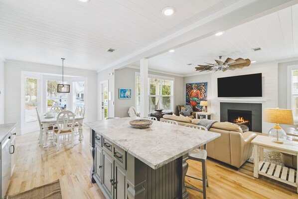 A spacious living area with a fireplace, a large island with a bowl, and a sofa.