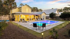 Una propiedad residencial con piscina, mobiliario exterior y un patio bien iluminado.