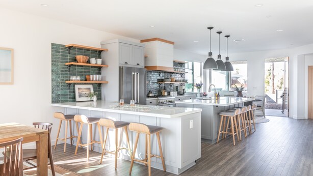 Eine moderne Küche mit einer großen Kochinsel, Barhocker und einem Essbereich mit Holztisch.