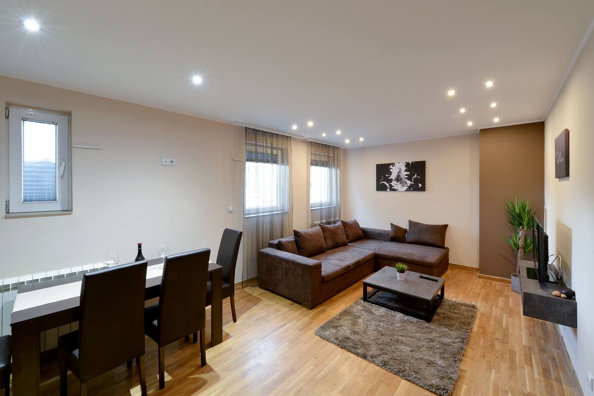 A modern living room with a sectional sofa, dining table, chairs, and a coffee table.
