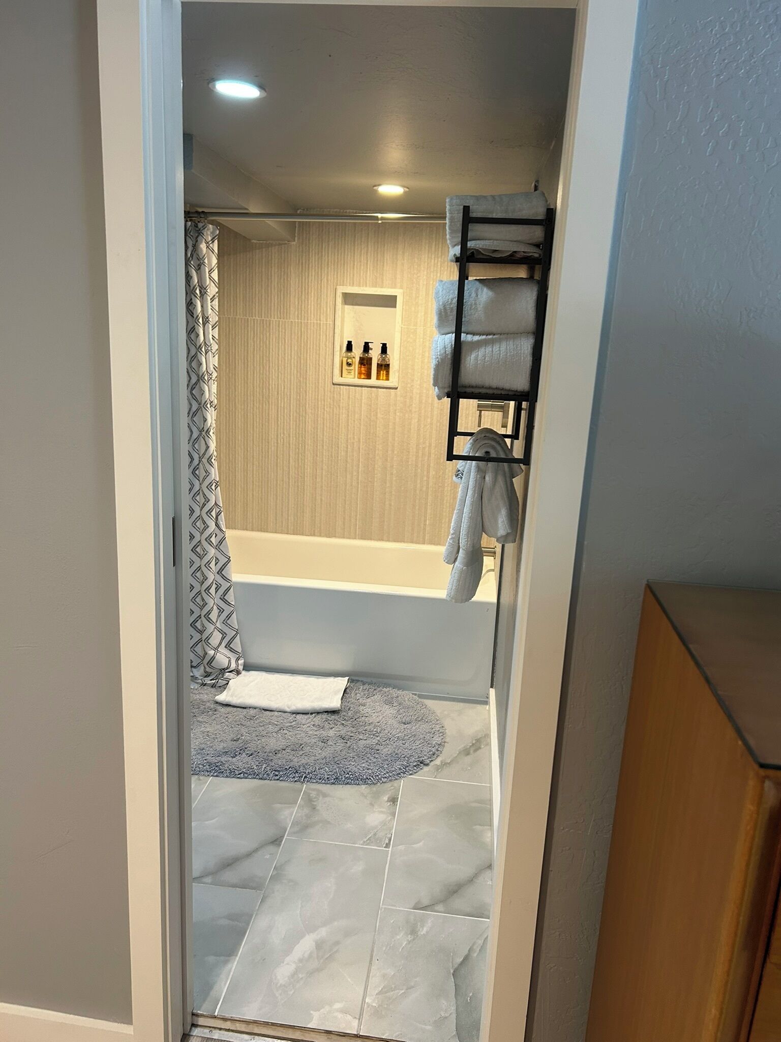 A bathroom with a bathtub, a shower area, and a towel rack.