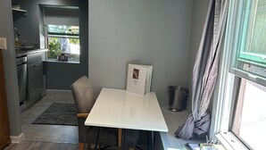 Eine kompakte Küche mit Essbereich, einem Fenster mit Vorhängen und einem kleinen Tisch mit einem Buch.