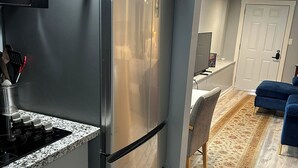 Eine Küche mit einem Edelstahlkühlschrank, einem eingebauten Backofen und einer Arbeitsplatte aus Granit.