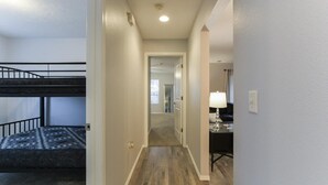 Un couloir étroit, avec un lit superposé sur la gauche et un bureau avec une lampe sur la droite.