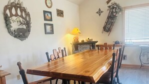 Un comedor con una larga mesa de madera, sillas, una chimenea y adornos en la pared.