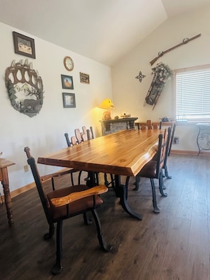 A dining room with a long wooden table, chairs, a fireplace, and wall decorations.