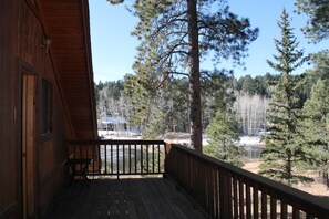 Overlooking a serene forest, this cabin features a balcony with a bench and a window.