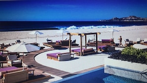 A beachside resort with outdoor seating areas, a pool, and a view of the ocean.