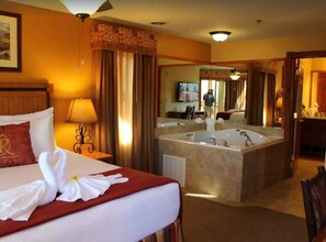 Relax in a spacious room with a large bed, bathtub, and wall-mounted TV.