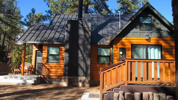A log cabin with a porch, a chimney, and a small deck. - 2+2, Spa, Sleeps 6, Walk 2 Hiking & Biking Trails, Pet Friendly on North Shore (Big Bear)