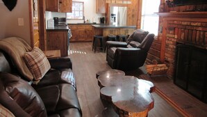 A cozy living room with a leather sofa, a recliner, and a coffee table. There is a fireplace and a television mounted on the wall. - 2+2, Spa, Sleeps 6, Walk 2 Hiking & Biking Trails, Pet Friendly on North Shore (Big Bear)