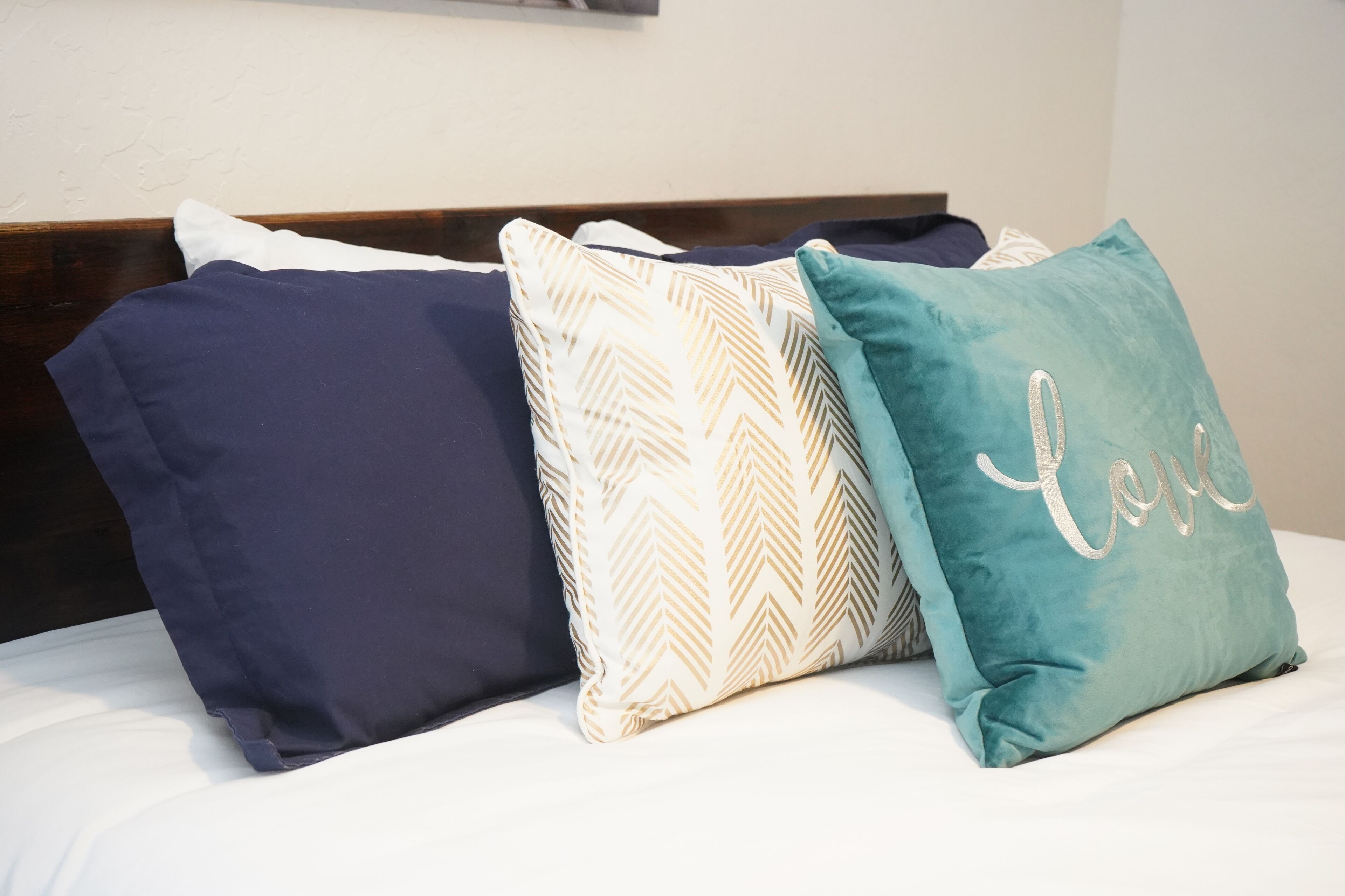 A bed with three pillows in different colors and patterns.