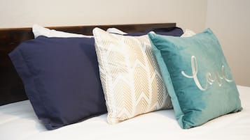 A bed with three pillows in different colors and patterns.