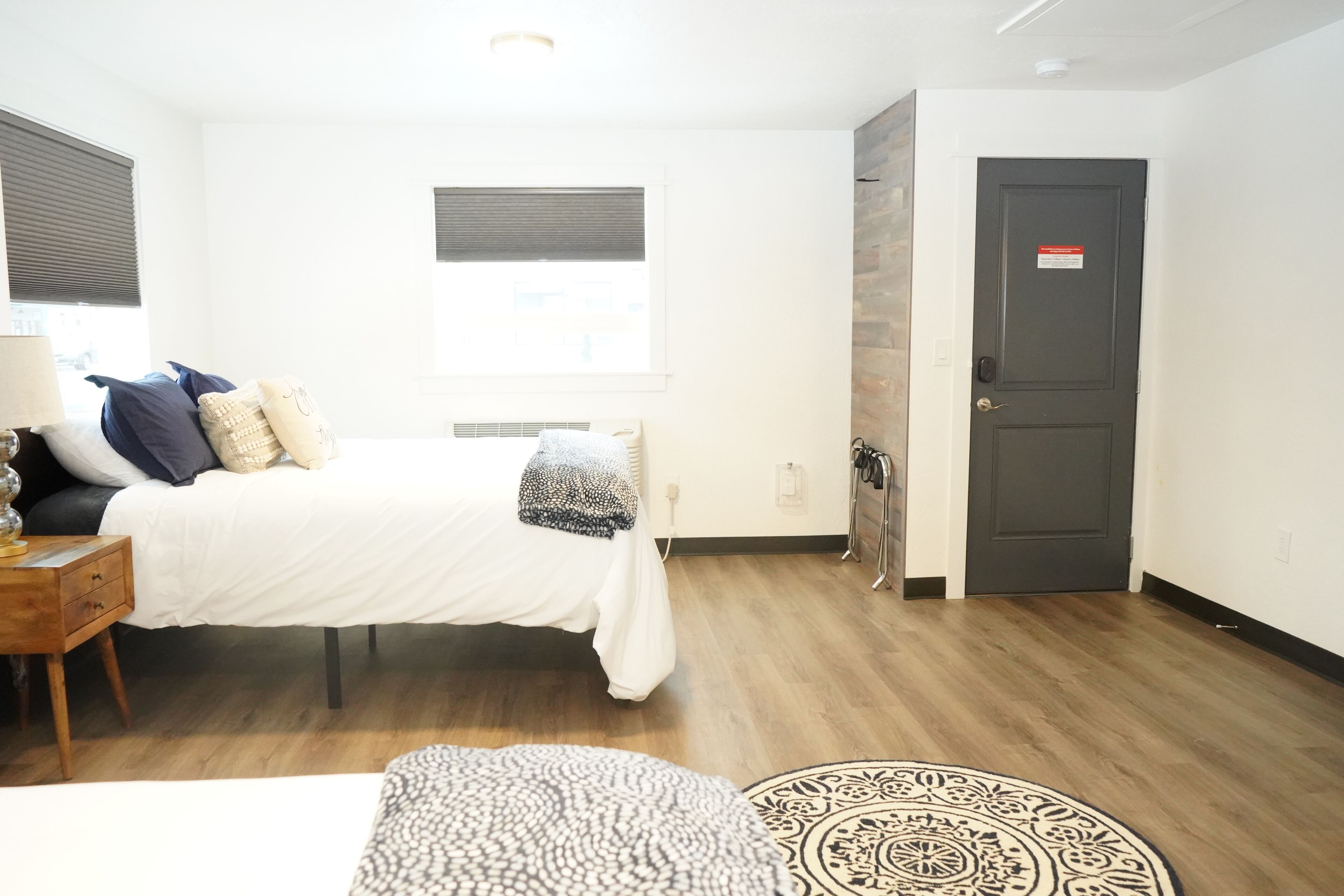 A bedroom with a bed, bedside table, lamp, and a patterned rug.