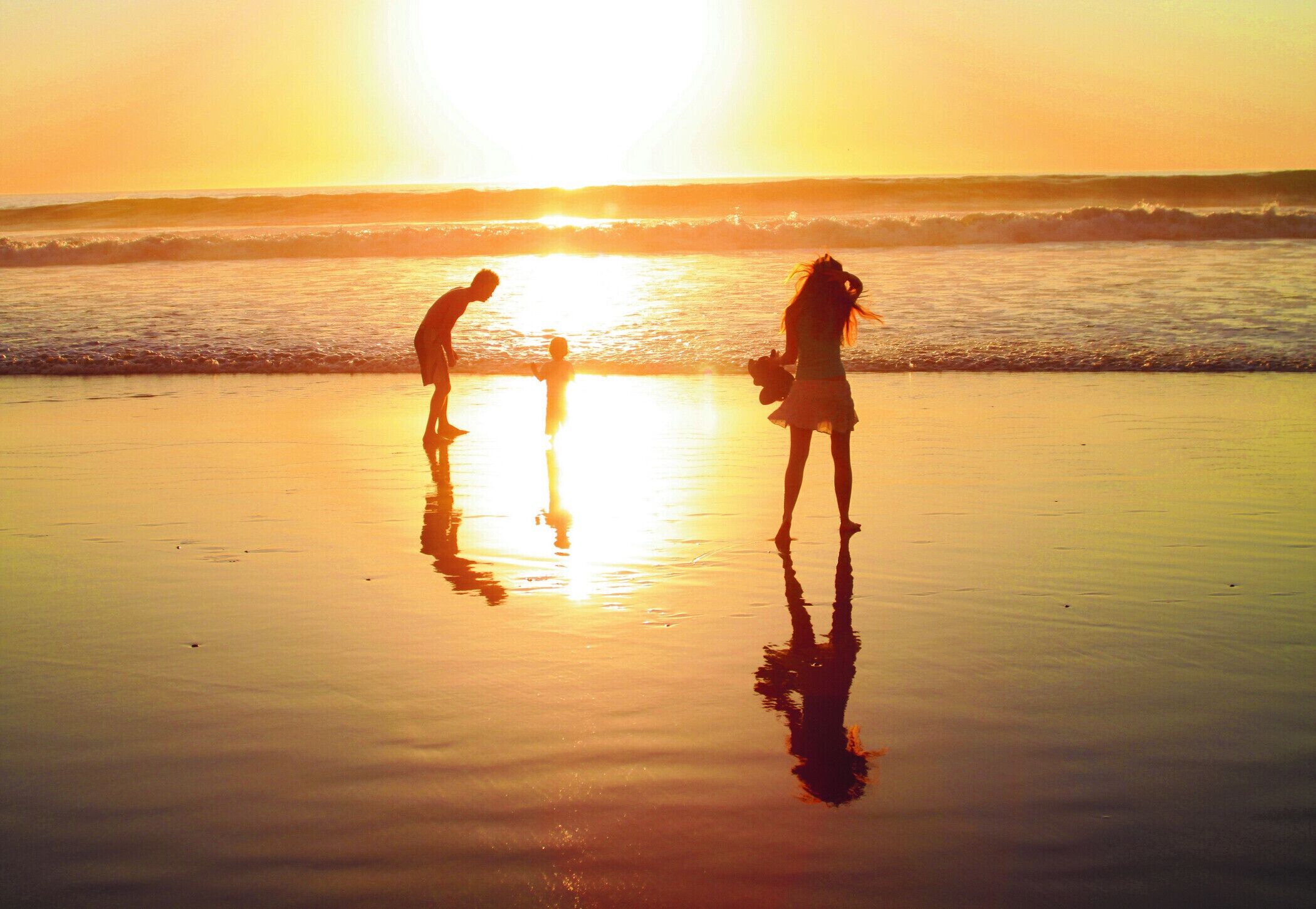 Escena de playa con gente al atardecer.