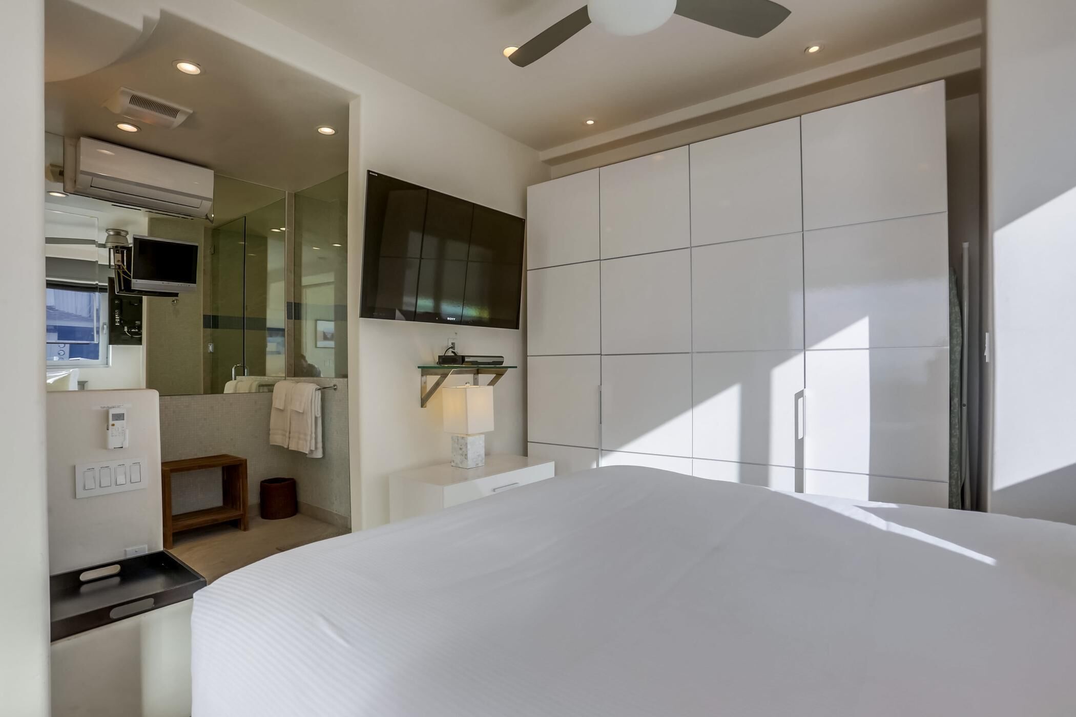 Una habitación de hotel moderna con una cama grande, televisión, espejo y armario.