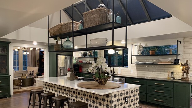 Una cocina moderna con una isla central, taburetes de bar y un techo alto con vigas a la vista.