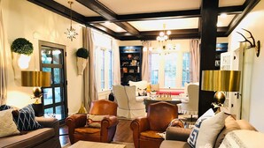 Una sala acogedora con sillones de cuero, una mesa de centro de madera y un sofá. Se observa una estantería y un candelabro.