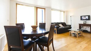 Ein modernes Wohnzimmer mit einem runden Esstisch, einer dunkelbraunen Ledersofa und einem flachbildfernseher, der an der Wand montiert ist.