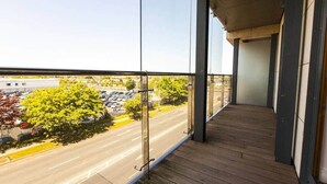 Ein Balkon mit Blick auf einen Parkplatz und Bäume.