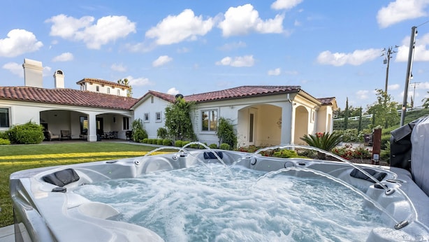 Un espace avec un jacuzzi, avec une maison en arrière-plan.