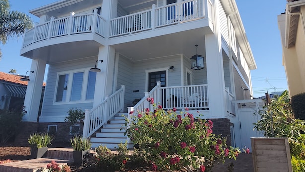 A two-story house with a balcony, a front porch, and a staircase leading to the entrance.