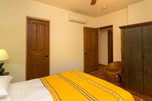 A bedroom with a bed, a wooden wardrobe, a door, and a chair. - Casa De La Alegria 3BR by Casago (Loreto)