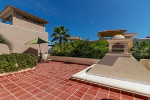 A rooftop patio with red tiles, a green umbrella, and a white dome structure. - Casa De La Alegria 3BR by Casago (Loreto)