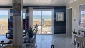 Un grand salon avec vue sur la plage, un panneau d’accueil et un téléviseur.