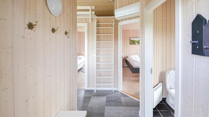 Een houten interieur met een centrale trap, een bed en een badkamer.
