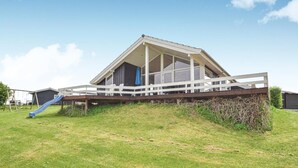 Een modern huis met een schuin dak, een overdekte veranda en een blauwe glijbaan in de tuin.