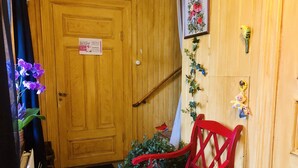 A wooden door with a sign, a red chair with a cushion, and a plant with purple flowers. - Charming 1-bed Studio in Avesta (Avesta)
