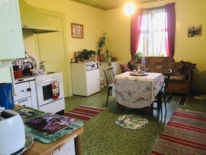 A compact kitchen with a stove, refrigerator, and dining area with a table and chairs.