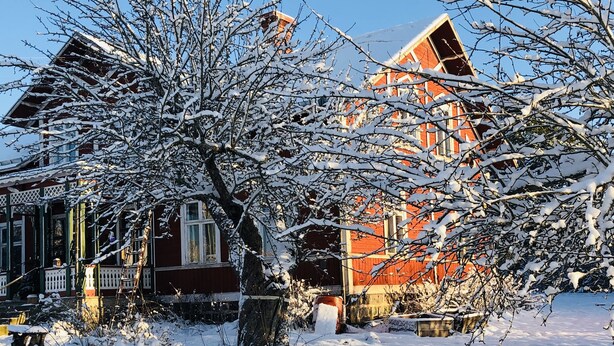 A snow-covered house with a porch and a red roof. - Charming 1-bed Studio in Avesta (Avesta)