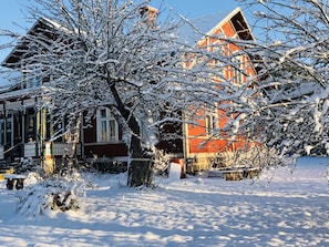 A snow-covered house with a porch and a red roof.