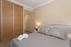 Ein Schlafzimmer mit einem Bett, einem Nachttisch, einer Lampe und einem Holzschrank.