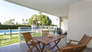 A wooden table and chairs on a balcony with a pool view. - Brisas B2, 2 bedrooms, beach at 50m, by Bookindenia (Dénia)