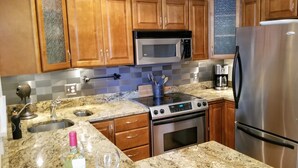 Una cocina moderna con armarios de madera, un refrigerador de acero inoxidable, un microondas, un horno y una cafetera.