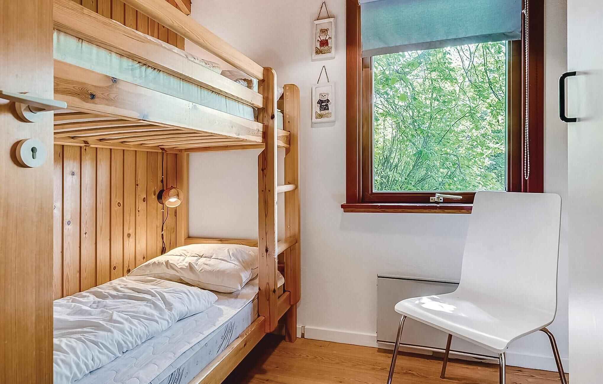 A bunk bed room with a window and a white chair.