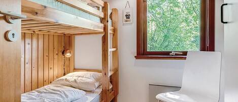 A bunk bed room with a window and a white chair.