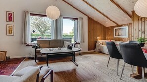 Ett mysigt rum med ett träpanelat tak, en soffa, ett matbord med stolar och en säng.