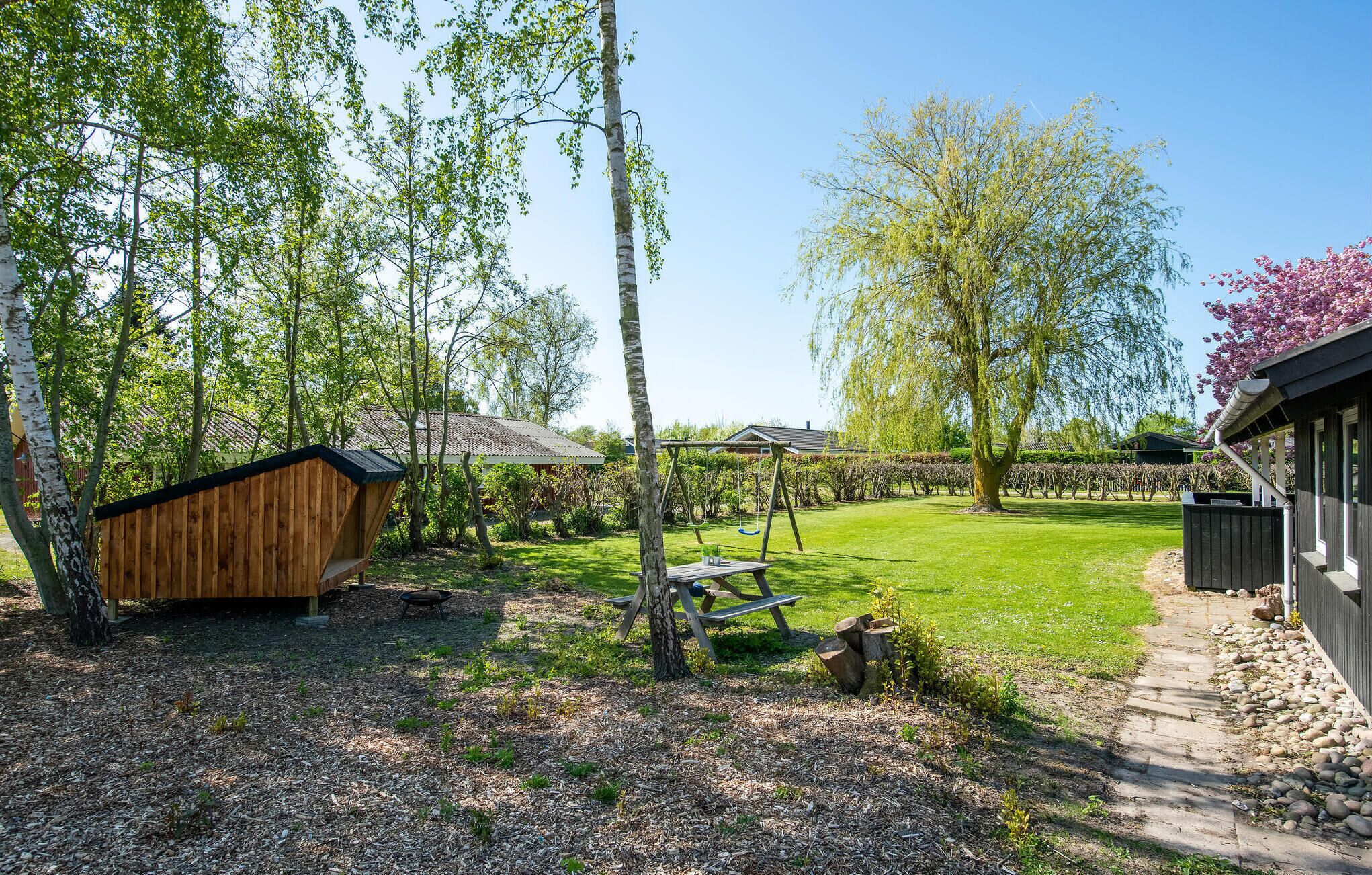 A backyard with a wooden shed, a swing set, and a lawn.