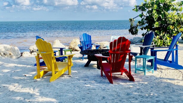 A beach with colorful Adirondack chairs and a string of lights. - Welcome to Paradise! (Key Largo)