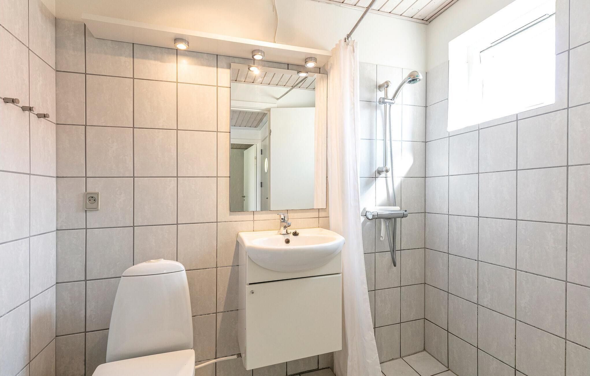 Une salle de bain moderne avec un lavabo blanc, un miroir et une douche.