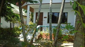A white building with a porch, surrounded by tropical vegetation. - Baan Coconut (Choeng Thale)