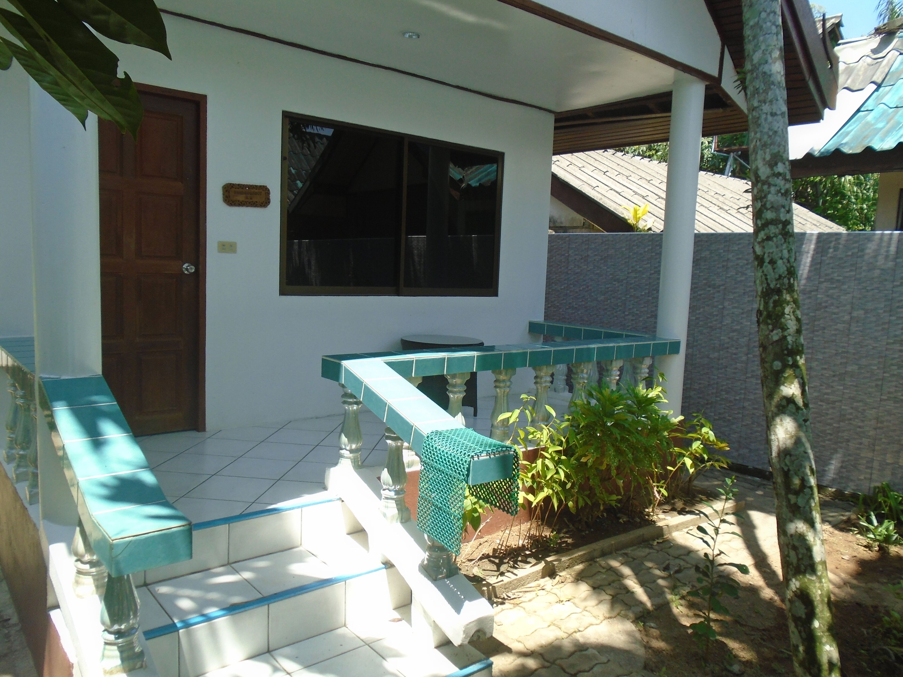A house with a tiled porch, a wooden door, and a window.