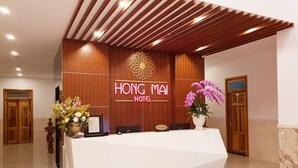 En hotellreception med modern design, en skylt med texten ”reception” och en blomsterdekoration.