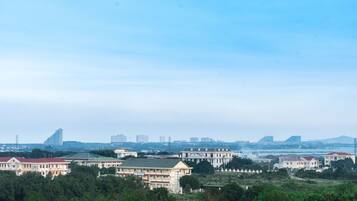 A residential area with multiple buildings, including a large white building with a green roof and several smaller houses with red roofs.